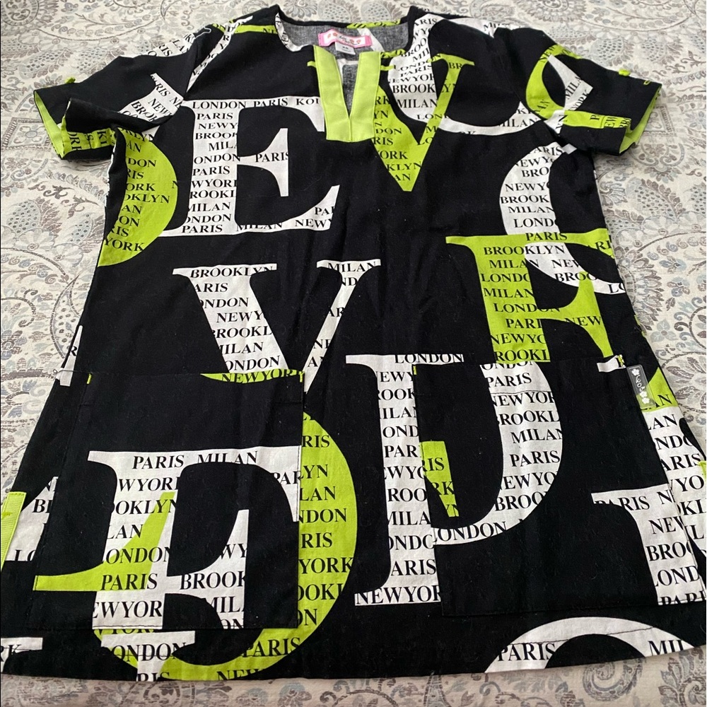 Koi XS uniform top in green, black and white with wording.
